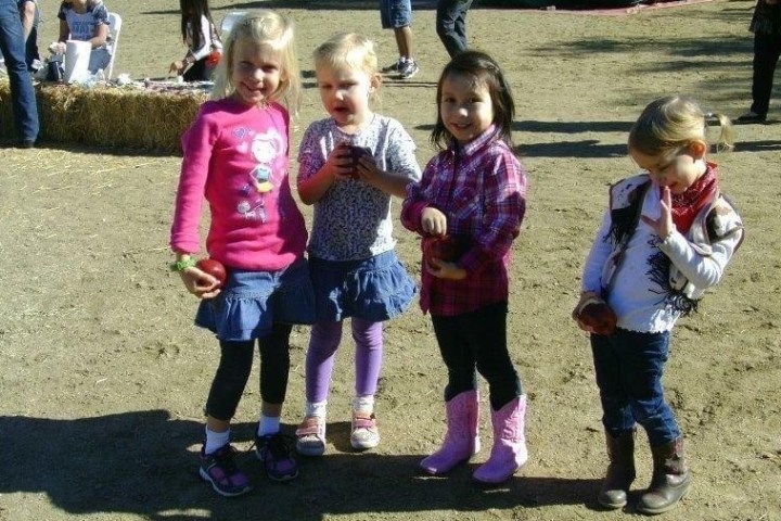 a group of people standing next to a little girl holding a football ball